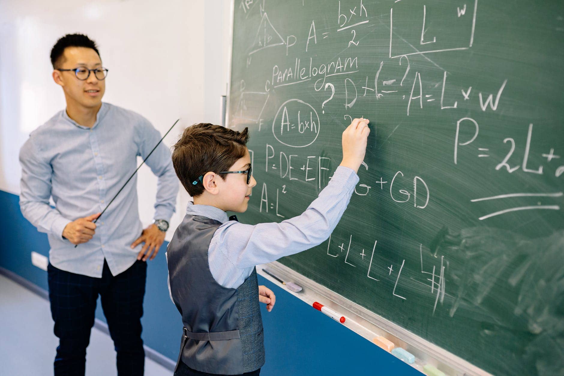 a boy writing his answers on the blackboard
